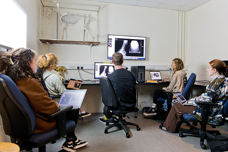 A group of students sitting around a computer with a lecturer